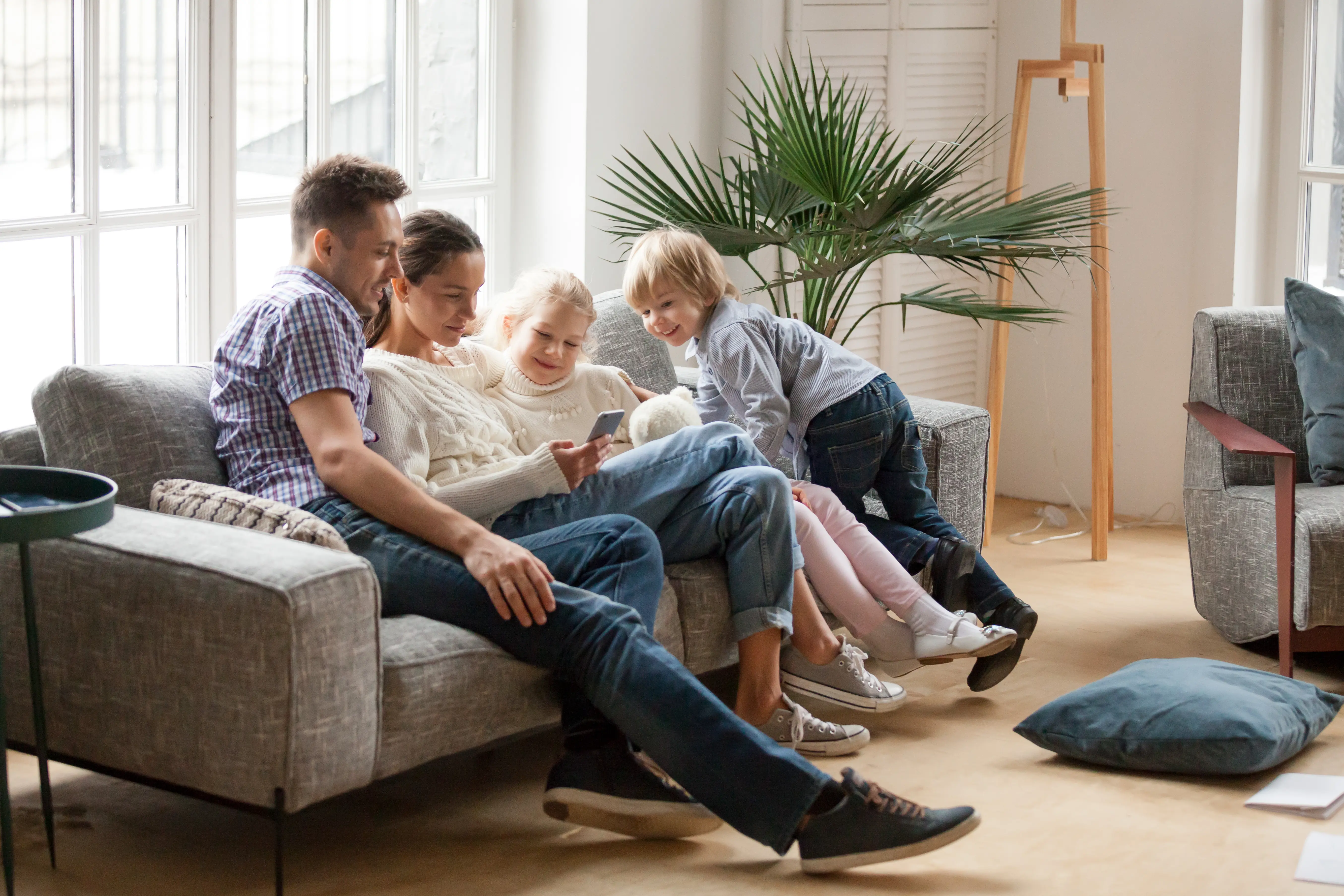 A group of people sitting together on a couch in a bright living room