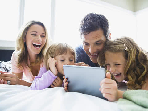 A smiling family using a tablet